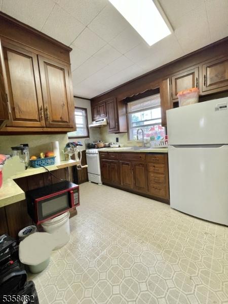 277 Watchung Ave, North Plainfield Boro, NJ 07060 - kitchen featuring white appliances, light countertops, light flooring, a sink, and under cabinet range hood