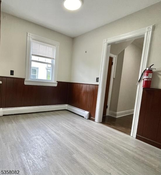 277 Watchung Ave, North Plainfield Boro, NJ 07060 - unfurnished room with wood finished floors, baseboard heating, a wainscoted wall, and wood walls