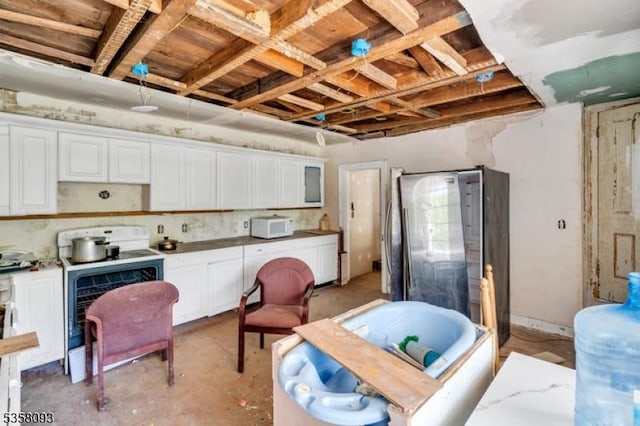 kitchen featuring white microwave, concrete floors, and white cabinets