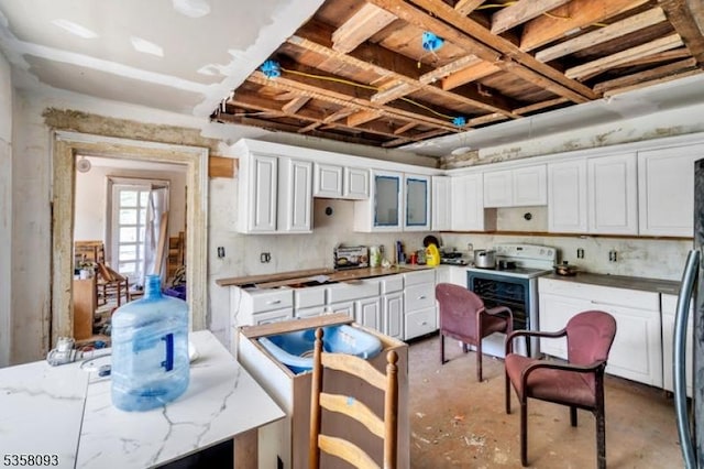 kitchen featuring concrete flooring, white cabinetry, range with electric cooktop, light stone counters, and fridge