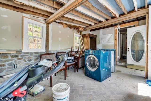 laundry room with healthy amount of natural light and brick flooring