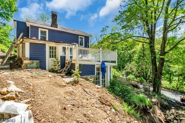 rear view of property featuring a chimney and a deck