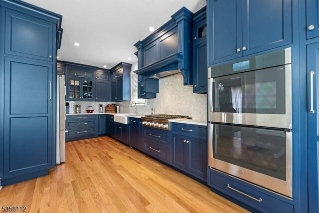 208 W Milton Ave, Rahway City, NJ 07065 - kitchen with stainless steel appliances, blue cabinets, light countertops, a sink, and glass insert cabinets