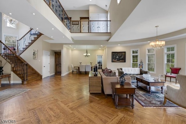 living room featuring a chandelier, stairway, a towering ceiling, baseboards, and healthy amount of natural light