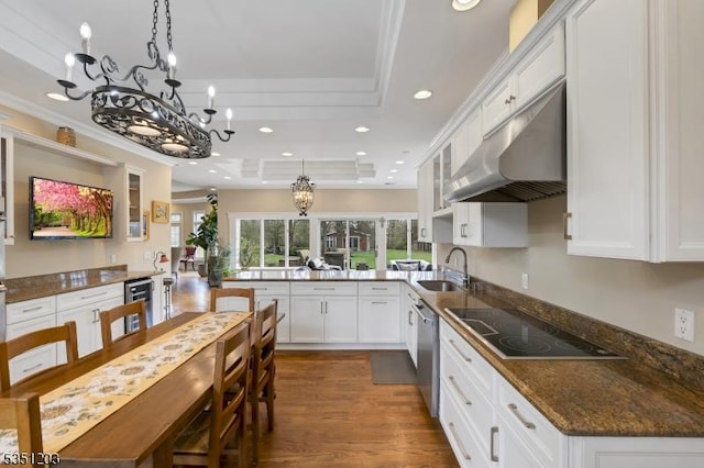 kitchen featuring black electric cooktop, under cabinet range hood, a raised ceiling, wine cooler, and a chandelier