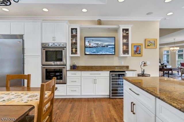 kitchen with beverage cooler, appliances with stainless steel finishes, white cabinets, wood finished floors, and recessed lighting