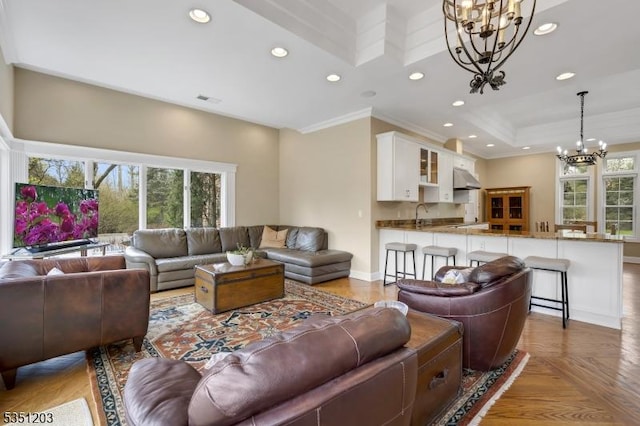 living area featuring a chandelier, plenty of natural light, recessed lighting, ornamental molding, and baseboards