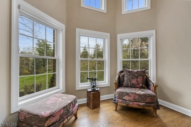 sitting room featuring wood finished floors, a towering ceiling, and baseboards