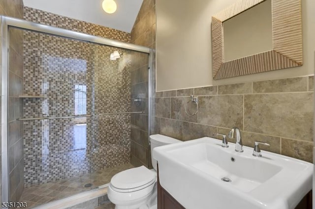 bathroom with toilet, a stall shower, vanity, and tile walls