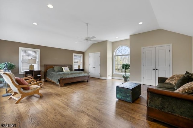 bedroom featuring vaulted ceiling, multiple closets, wood finished floors, a ceiling fan, and baseboards