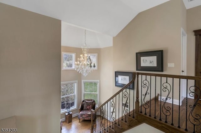 staircase featuring a chandelier, wood finished floors, high vaulted ceiling, and baseboards