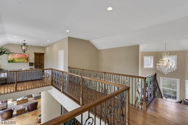 hallway with a chandelier, an upstairs landing, lofted ceiling, recessed lighting, and wood finished floors