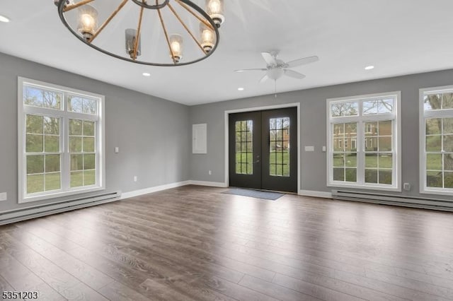 spare room featuring a baseboard heating unit, dark wood-style flooring, a chandelier, a ceiling fan, and french doors