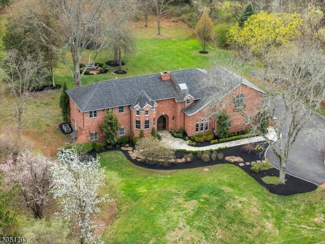 view of front of house featuring brick siding, a chimney, and a front yard