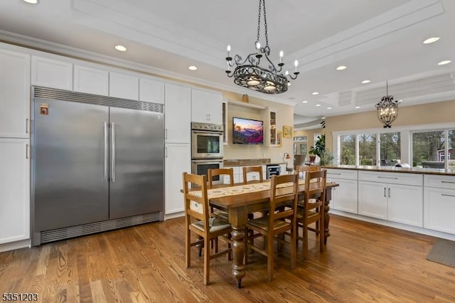 dining room with a chandelier, recessed lighting, wood finished floors, and crown molding