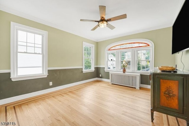 living room with radiator heating unit, wood finished floors, ceiling fan, baseboards, and ornamental molding