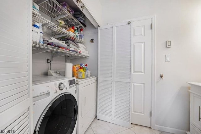 clothes washing area featuring independent washer and dryer, light tile patterned flooring, and baseboards