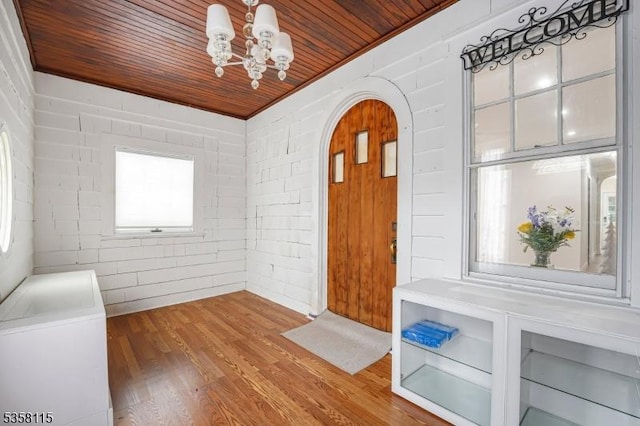 foyer with wooden ceiling, arched walkways, a chandelier, plenty of natural light, and wood finished floors