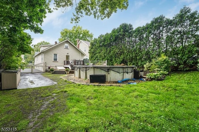 rear view of house with a covered pool, a yard, and a wooden deck