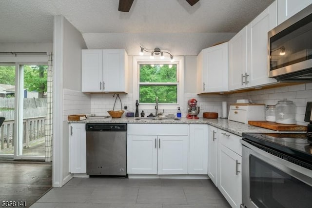 kitchen featuring appliances with stainless steel finishes, a sink, plenty of natural light, white cabinetry, and a textured ceiling