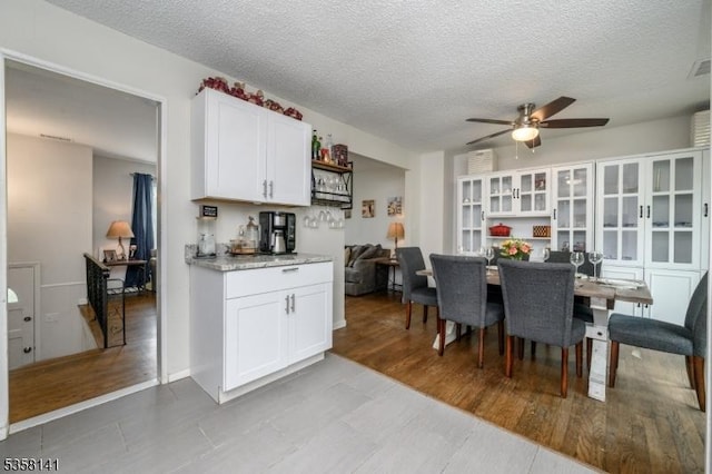 dining room featuring ceiling fan, a textured ceiling, and light wood finished floors