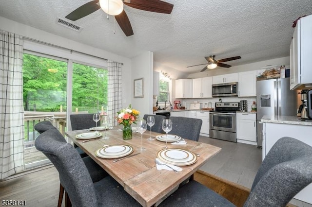 dining space featuring ceiling fan, a textured ceiling, and wood finished floors