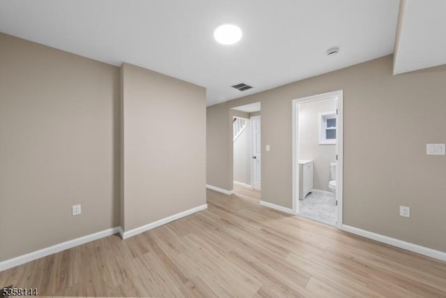 unfurnished bedroom with light wood finished floors, baseboards, and connected bathroom