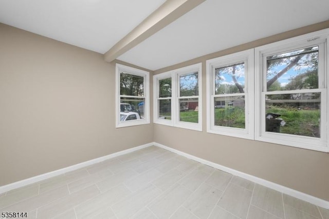 unfurnished sunroom with plenty of natural light, baseboards, and beam ceiling