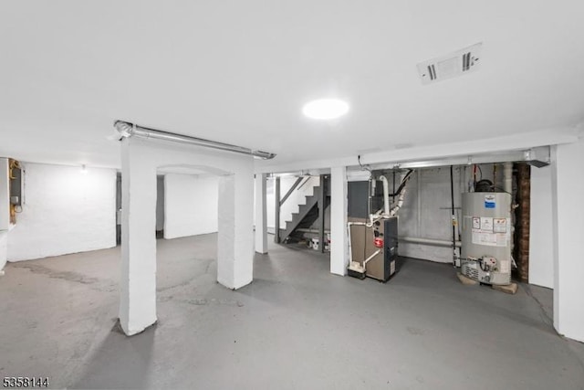 finished basement with water heater, stairs, and heating unit