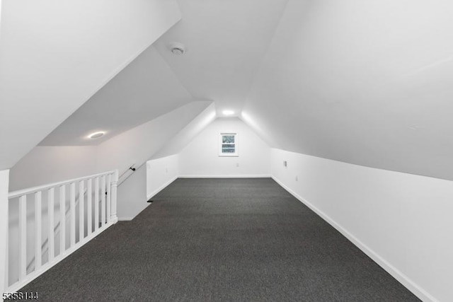 bonus room with lofted ceiling, dark carpet, and baseboards