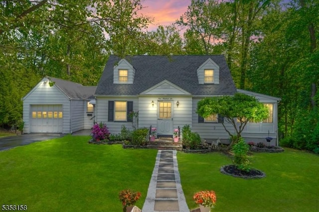 cape cod home featuring a garage, driveway, a front yard, and an outdoor structure