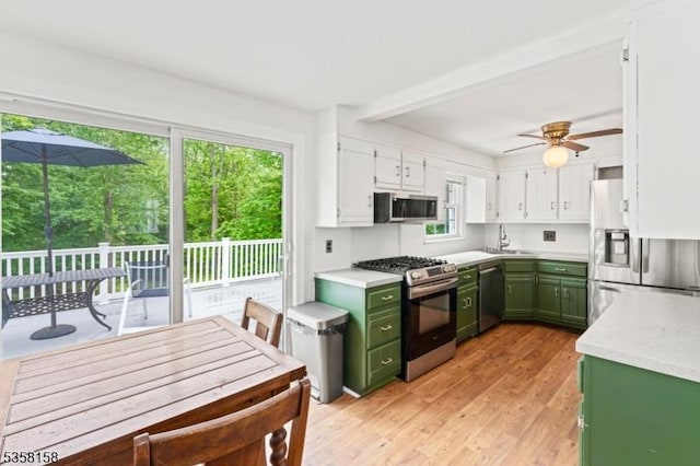 kitchen with green cabinetry, appliances with stainless steel finishes, a sink, light countertops, and white cabinets