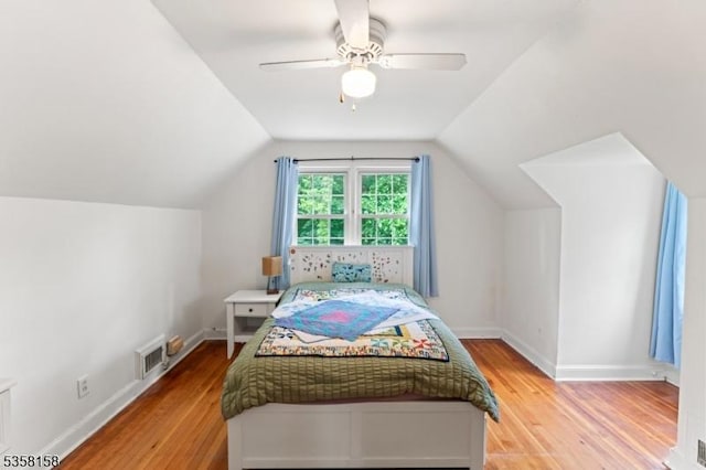 bedroom with light wood-type flooring, lofted ceiling, a ceiling fan, and baseboards
