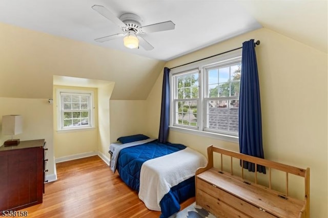 bedroom featuring lofted ceiling, wood finished floors, baseboards, and a ceiling fan