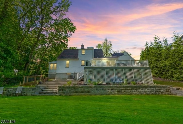 back of house featuring stairway, a deck, a lawn, and a chimney