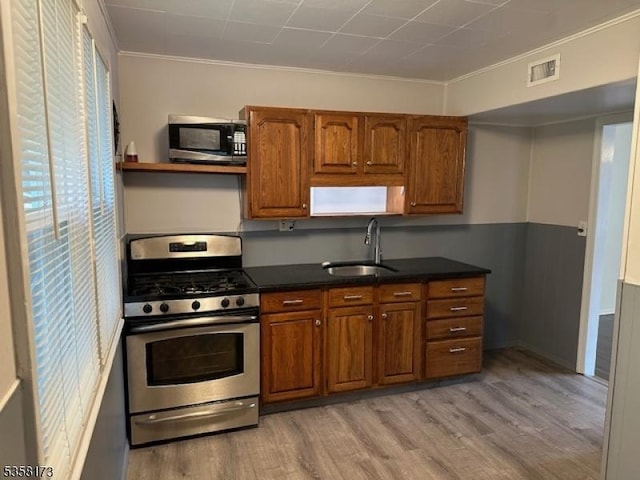 7 Cleveland Ave, Victory Gardens Boro, NJ 07801 - kitchen featuring stainless steel range with gas cooktop, a sink, brown cabinets, light wood-type flooring, and dark countertops