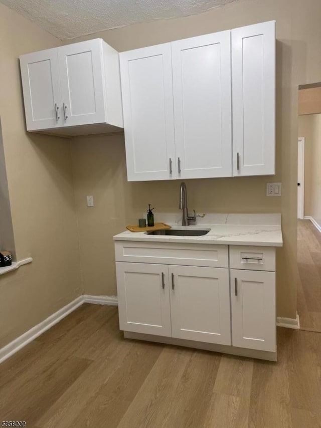 6601 Broadway Unit D6, West New York Town, NJ 07093 - kitchen featuring a sink, baseboards, light wood-style floors, white cabinetry, and a textured ceiling