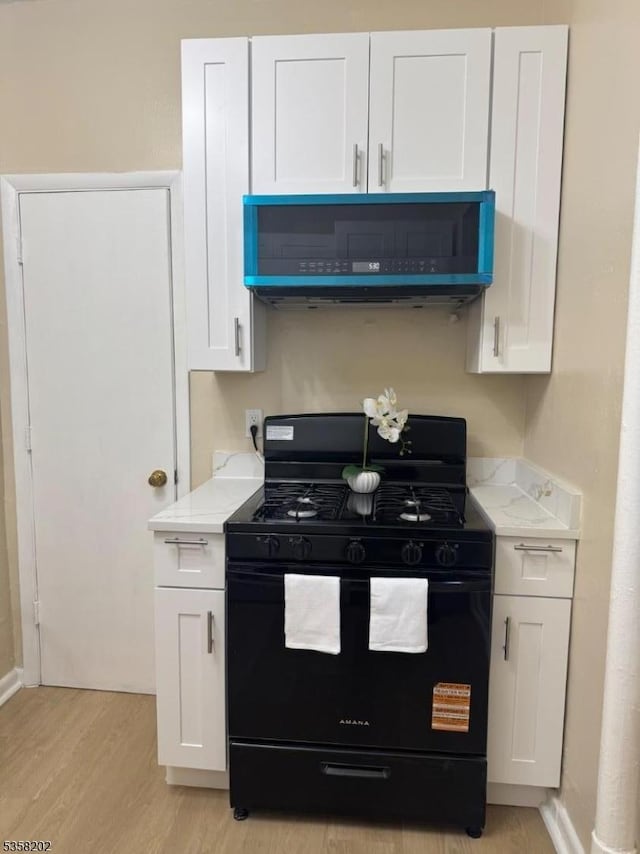6601 Broadway Unit D6, West New York Town, NJ 07093 - kitchen featuring black gas range, light wood finished floors, white cabinetry, and light stone countertops