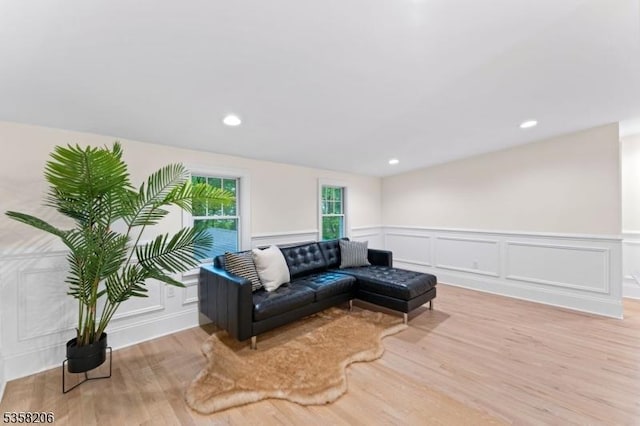 living room featuring wood finished floors, a decorative wall, wainscoting, and recessed lighting