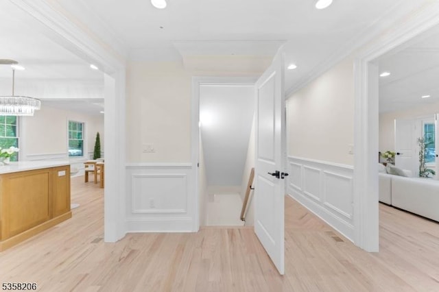 hall with a decorative wall, a wainscoted wall, light wood finished floors, and recessed lighting
