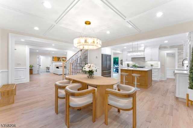 dining area featuring coffered ceiling, a chandelier, light wood-style floors, recessed lighting, and stairs