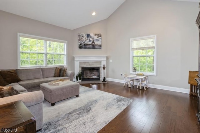 living room featuring a tile fireplace, baseboards, dark wood-style floors, and high vaulted ceiling