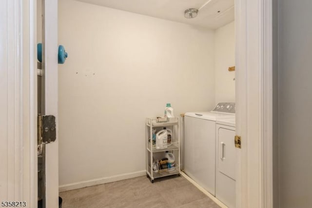 washroom with independent washer and dryer and baseboards