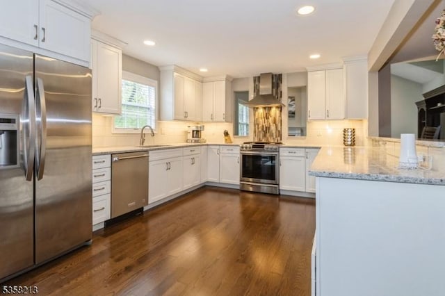 kitchen with stainless steel appliances, wall chimney exhaust hood, a sink, dark wood-type flooring, and recessed lighting