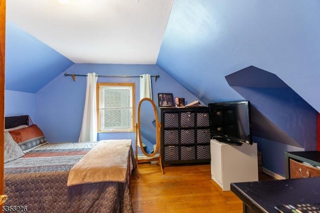 bedroom with wood finished floors and lofted ceiling