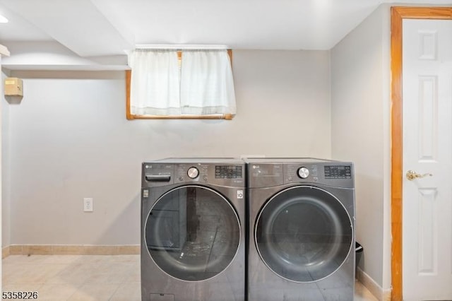 clothes washing area featuring washing machine and dryer, baseboards, and tile patterned flooring