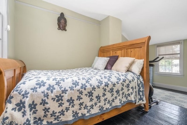 bedroom featuring hardwood / wood-style flooring, baseboards, and vaulted ceiling