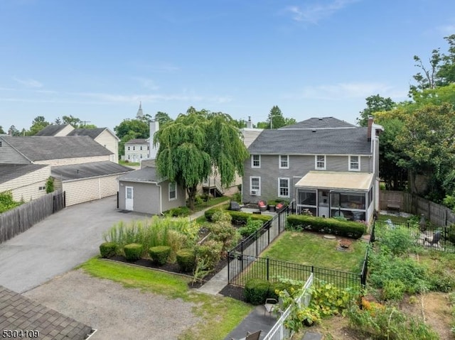 view of front of property with a sunroom, a detached garage, and a fenced backyard