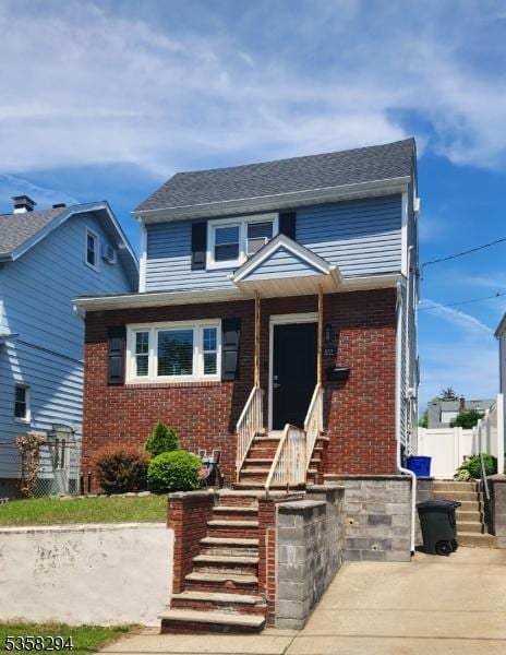 view of front facade with entry steps, brick siding, and fence