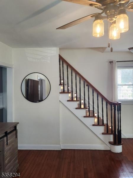 staircase featuring wood finished floors, baseboards, and a ceiling fan